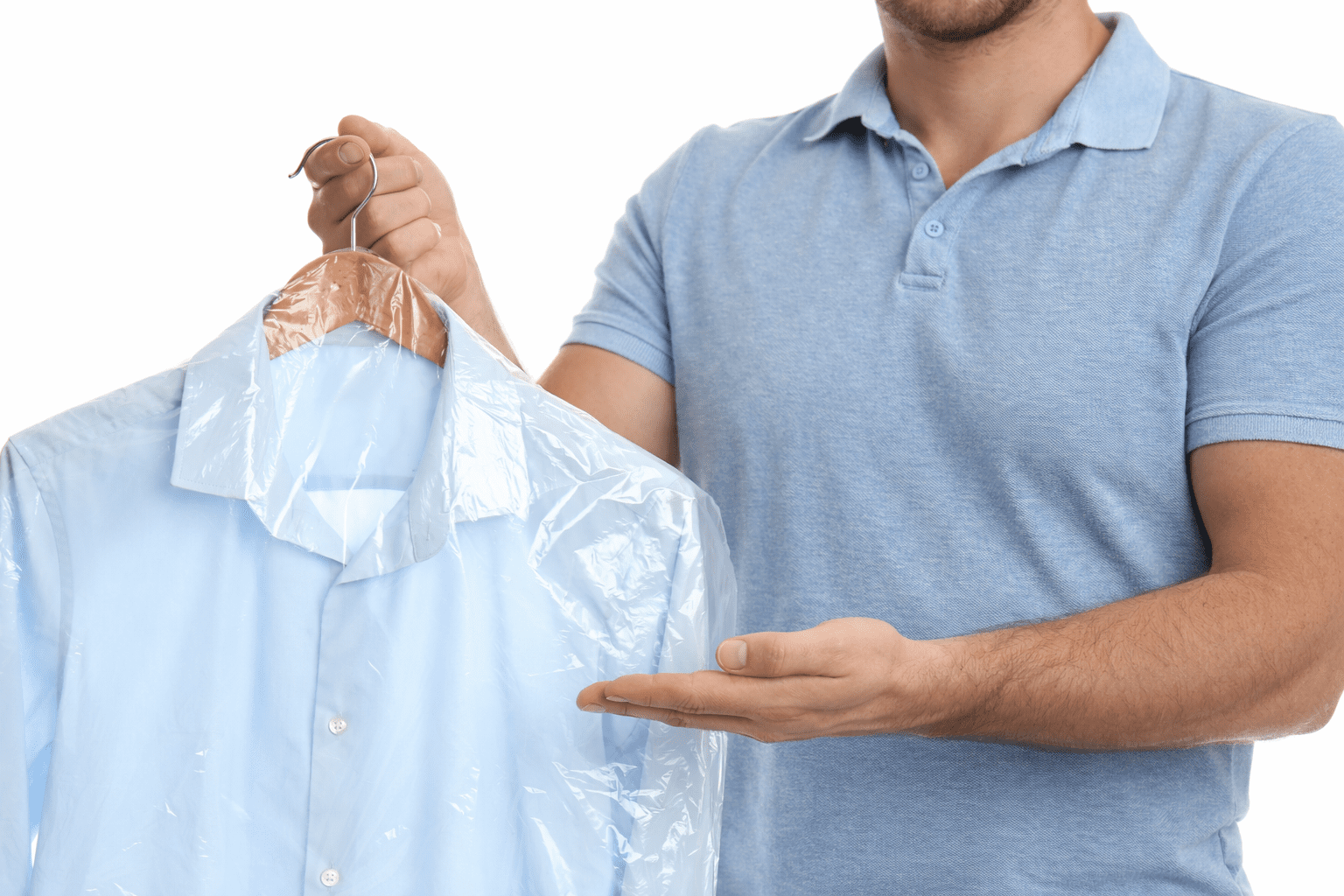 A person in a light blue polo shirt holds a dress shirt on a hanger covered in plastic, as if just picked up from the dry cleaner.